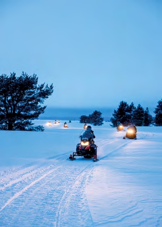 Excursion en motoneige au coucher du jour près de Luleå en Laponie suédoise, activité hivernale dans les paysages enneigés du Grand Nord.