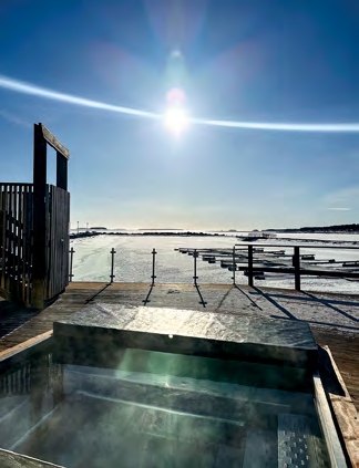 Bain nordique extérieur face à la mer gelée à Luleå, moment bien-être en hiver sous le soleil arctique.