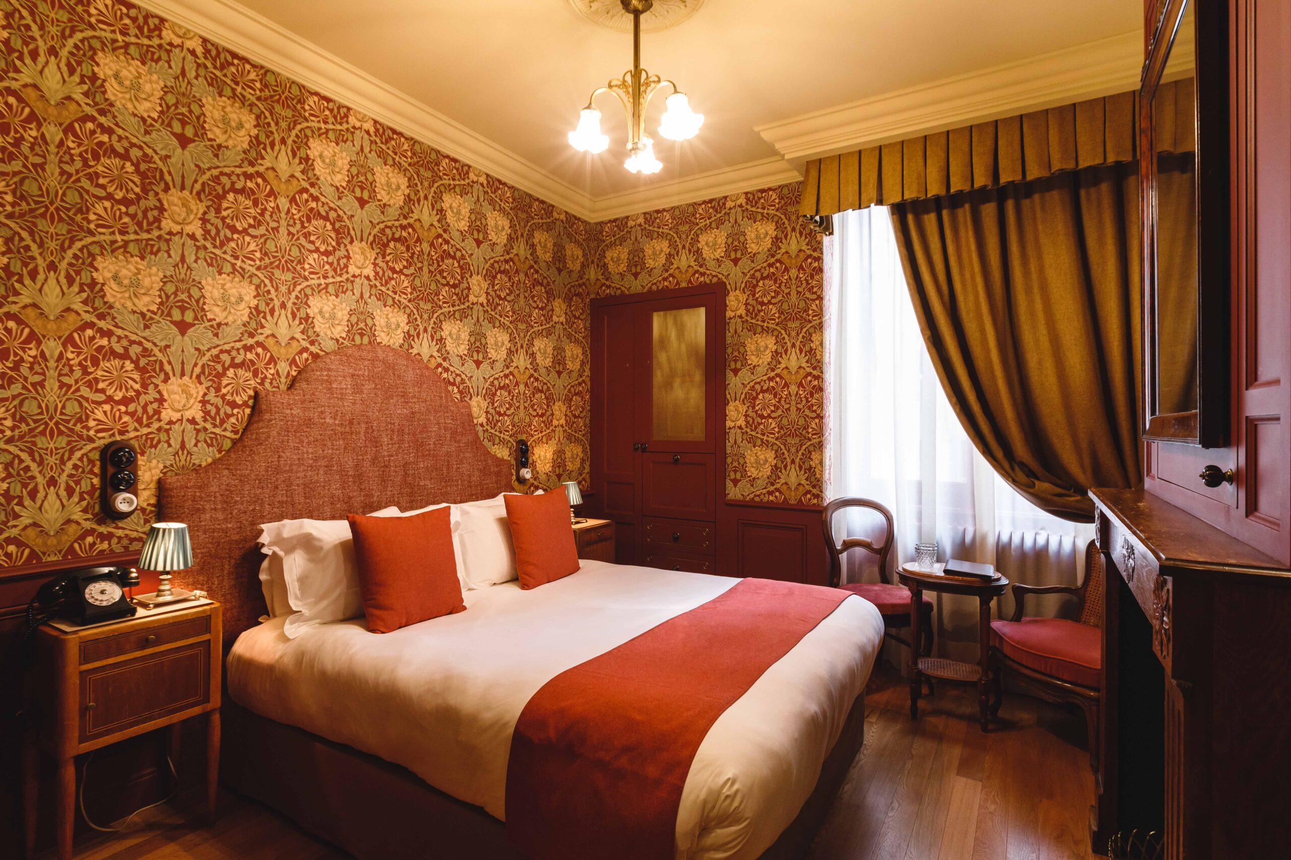 Chambre rouge bordeaux de l'Hôtel Bayard Bellecour Lyon, lustre à pampilles et mobilier chiné