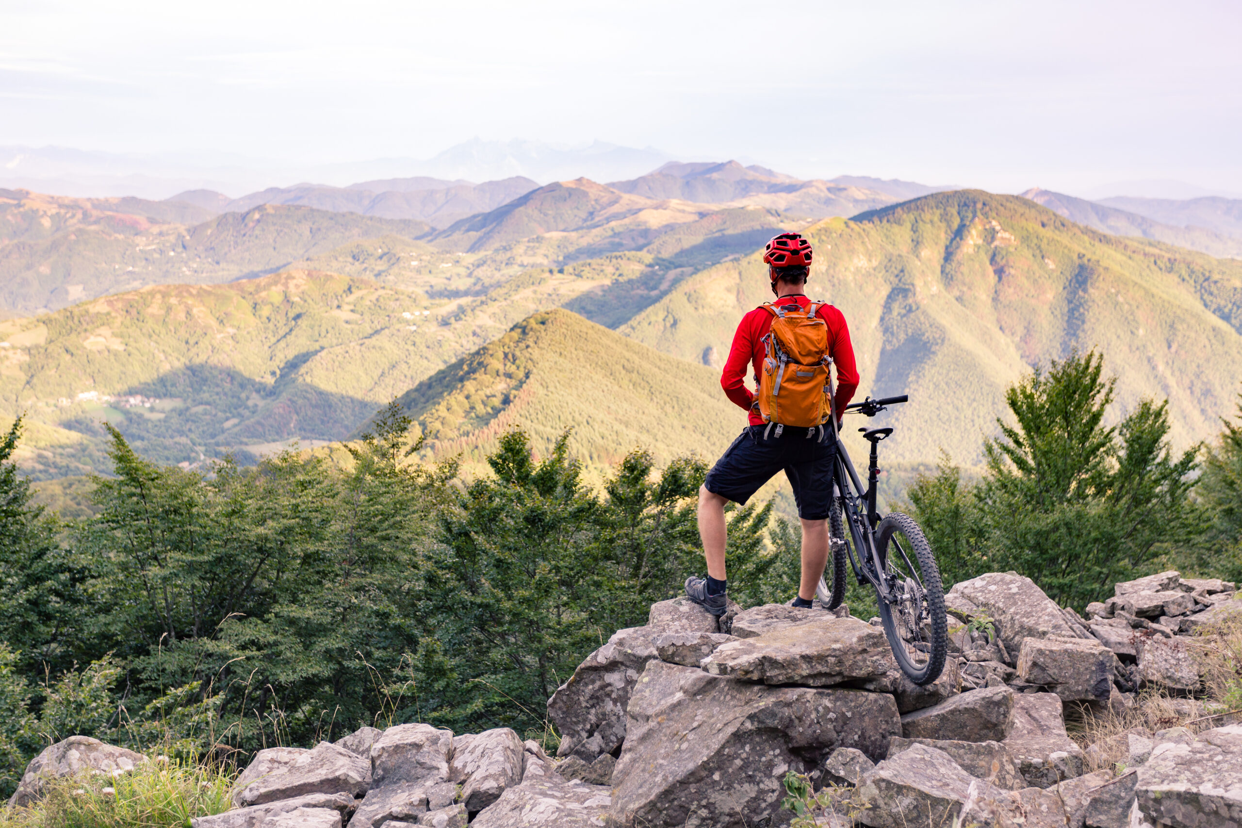 Cycliste en montagne avec vélo face à un panorama de collines et de paysages naturels