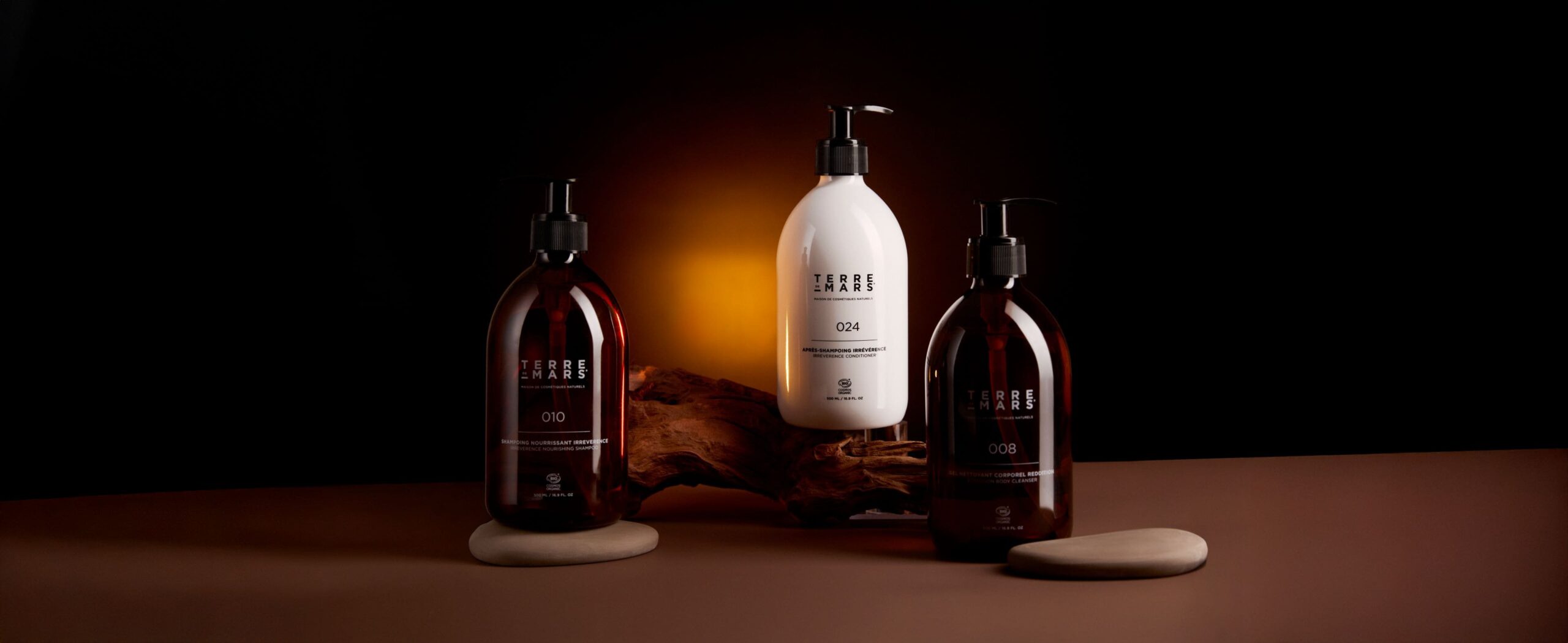 Gamme de soins Terre de Mars présentée sur fond sombre avec flacons ambrés et flacon blanc au design minimaliste.