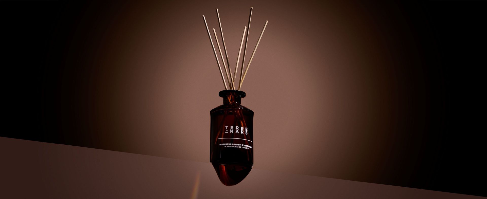 Diffuseur parfumé Terre de Mars avec tiges en rotin dans une ambiance intérieure élégante et tamisée.