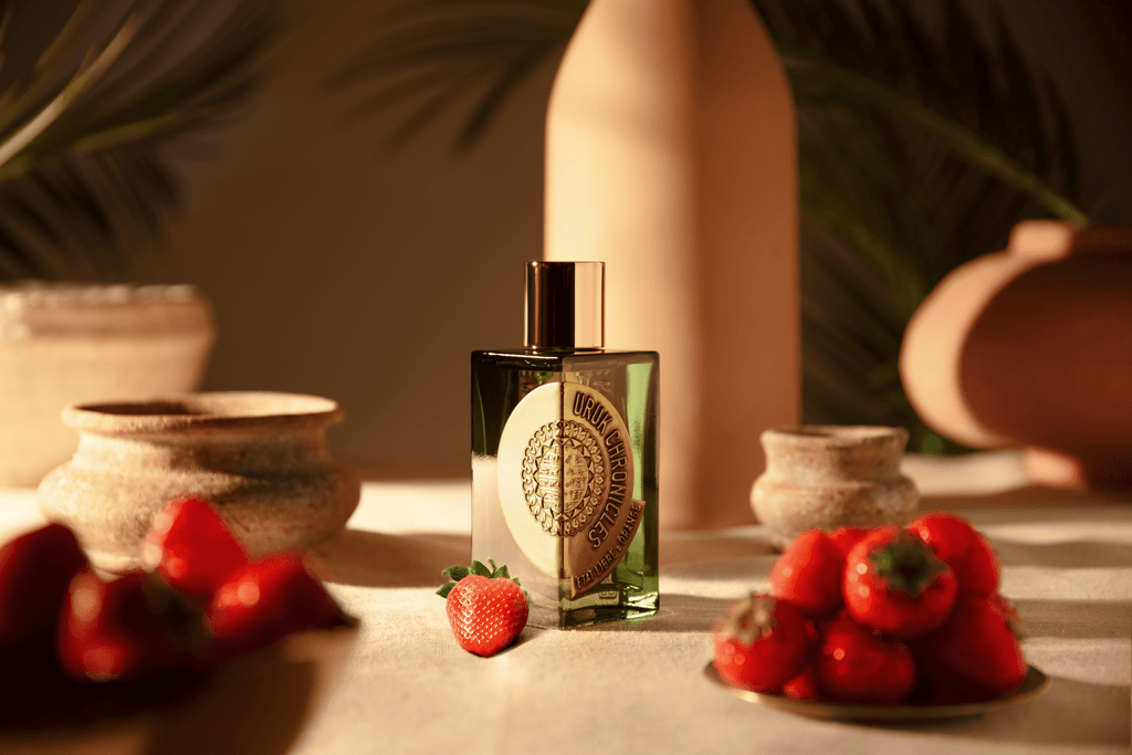 Flacon Uruk Chronicles entouré de fraises et de poteries en terre cuite évoquant les notes fruitées et la Mésopotamie