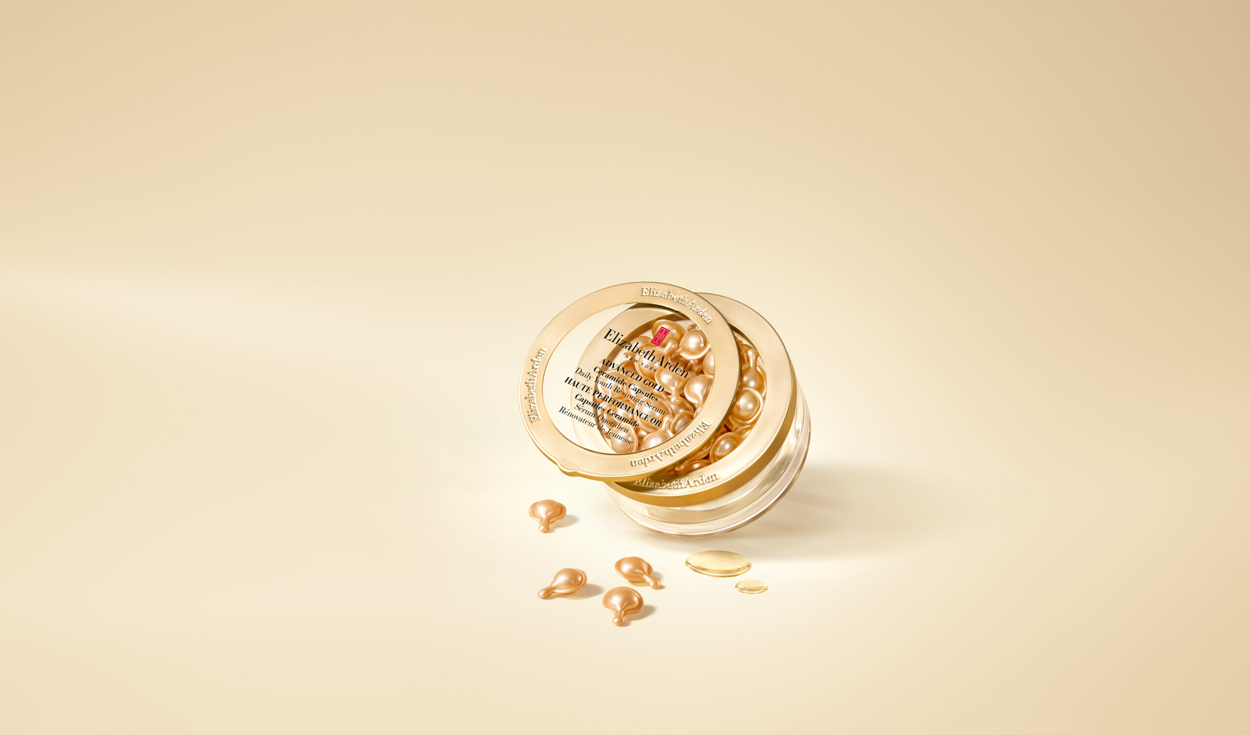 Pot Elizabeth Arden Advanced Gold Ceramide Capsules ouvert avec capsules dorées éparpillées, vue de dessus
