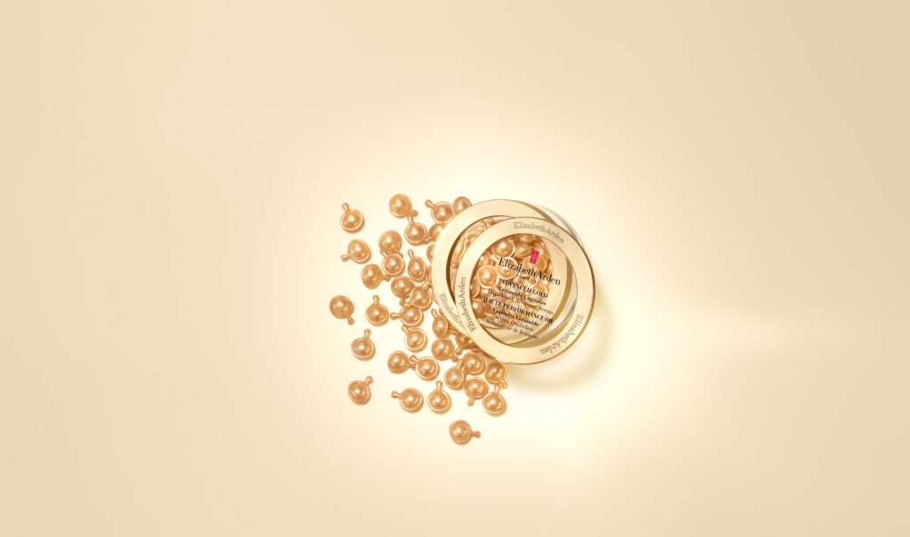 Pot Elizabeth Arden Advanced Gold Ceramide Capsules ouvert avec capsules dorées éparpillées, vue de dessus