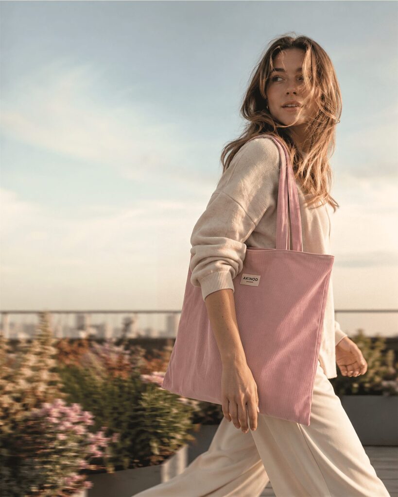 Femme portant le tote bag rose Akinod en velours côtelé sur un rooftop