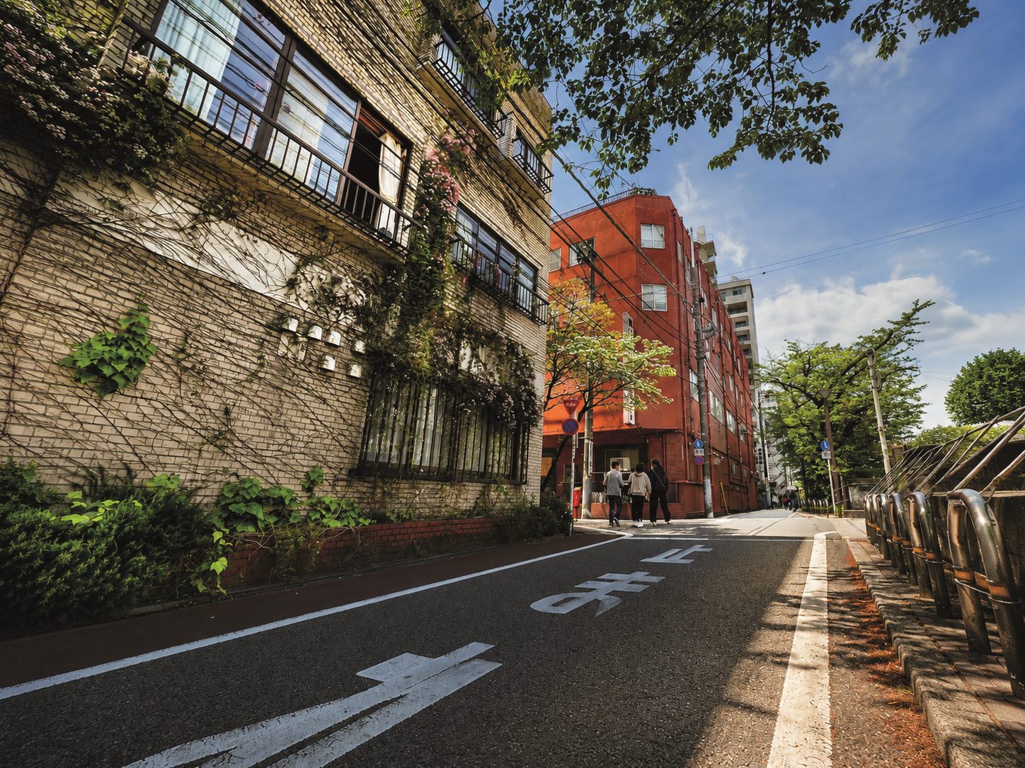 Rue tranquille du quartier de Nakameguro à Tokyo avec un immeuble rouge et de la végétation