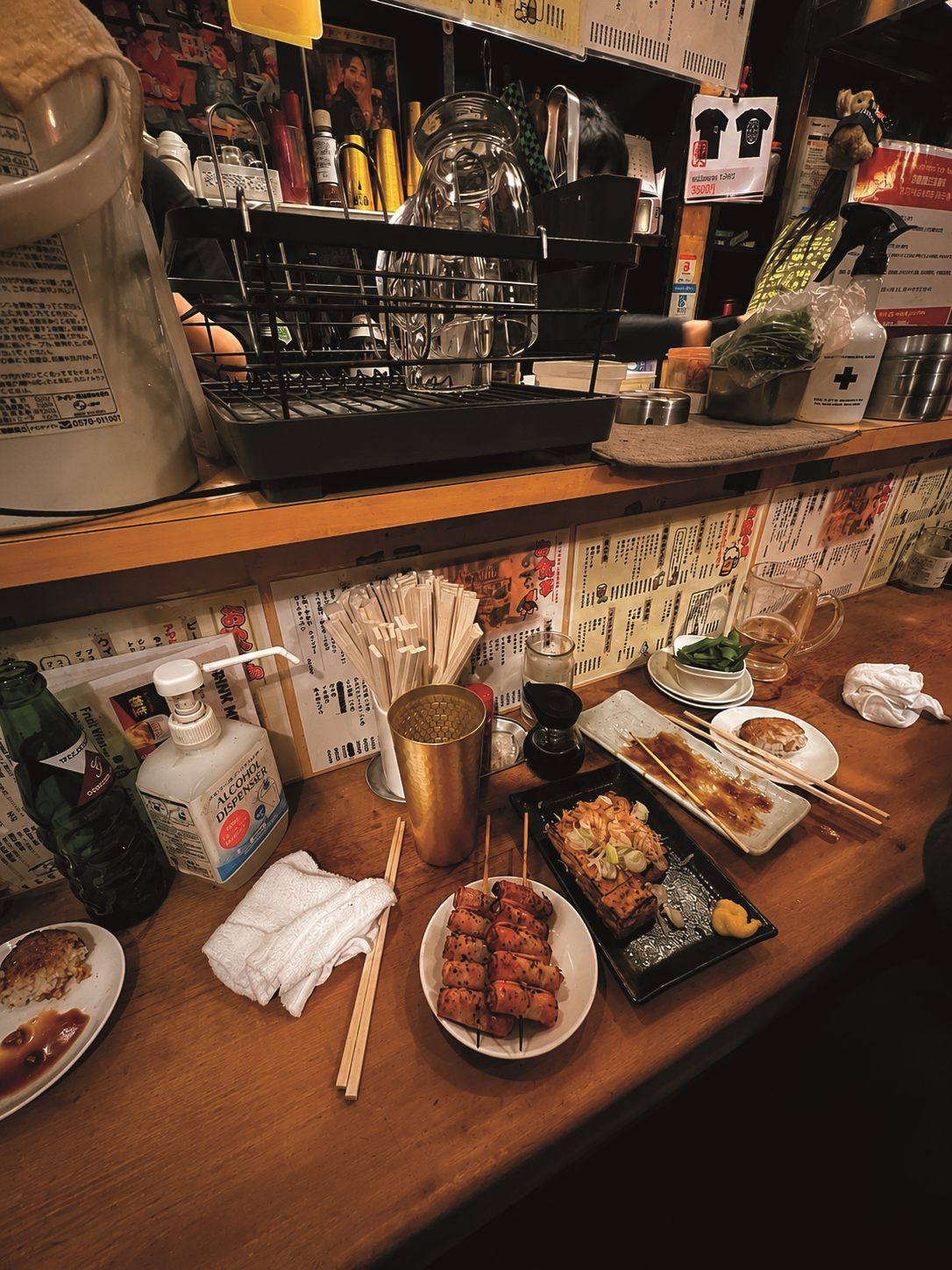 Comptoir d'un izakaya dans le Golden Gai à Shinjuku, Tokyo, avec brochettes et baguettes