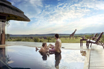 Couple dans une piscine de lodge face à une girafe, réserve de Madikwe, Afrique du Sud