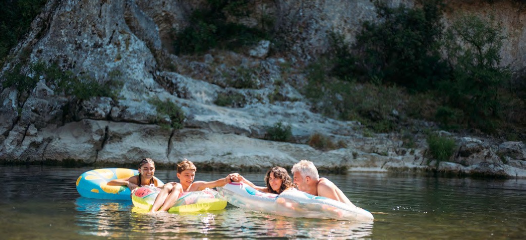 Famille sur des bouées dans la Cèze, au pied des rochers du Domaine de la Sablière