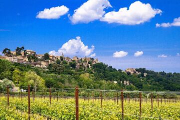 Le village perché de Ménerbes dominant un vignoble du Luberon sous un ciel bleu