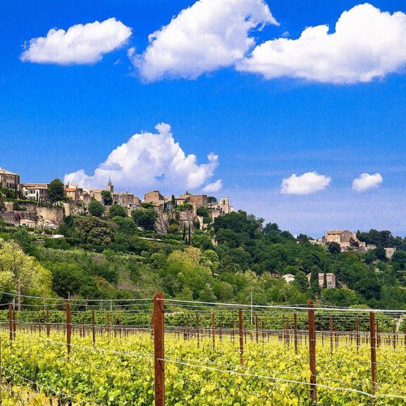 Le village perché de Ménerbes dominant un vignoble du Luberon sous un ciel bleu