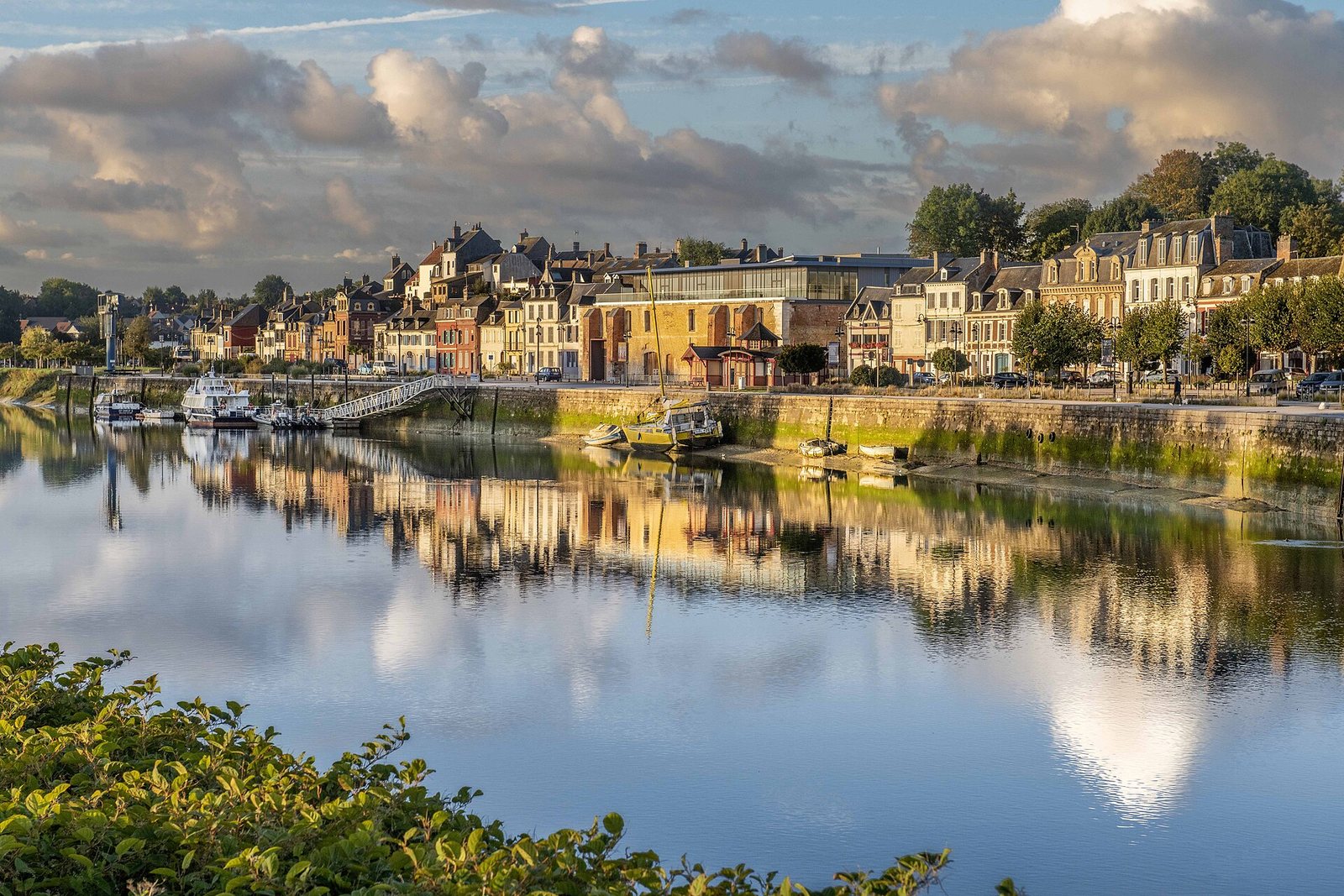 Les façades colorées du quai de Saint-Valery-sur-Somme se reflétant dans l’eau à marée basse