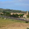 Train Intercités Bordeaux-Marseille tracté par une locomotive grise et orange, entre les vignes et le village de Névian, près de Narbonne