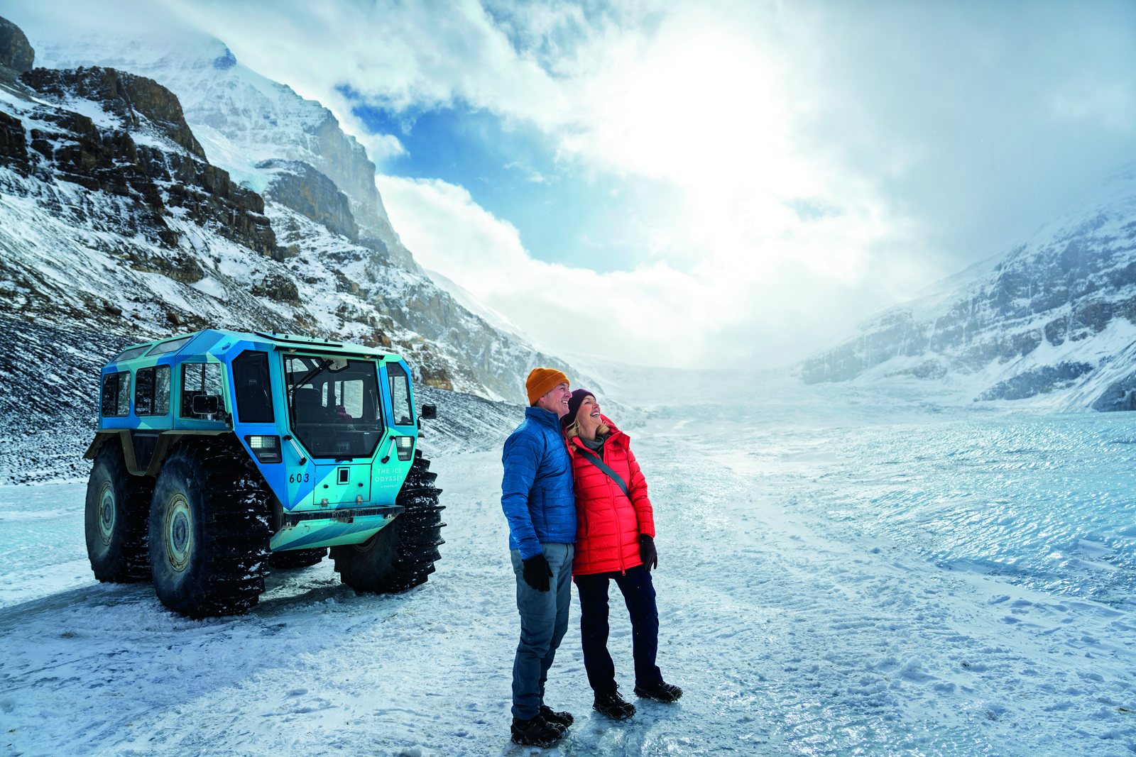 Couple sur le glacier Athabasca à côté d’un véhicule tout-terrain des glaces, Columbia Icefield
