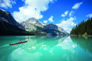 Canoë rouge sur les eaux turquoise du lac Maligne, sous des sommets enneigés, dans le parc national de Jasper