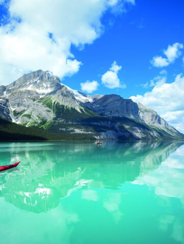 Canoë rouge sur les eaux turquoise du lac Maligne, sous des sommets enneigés, dans le parc national de Jasper