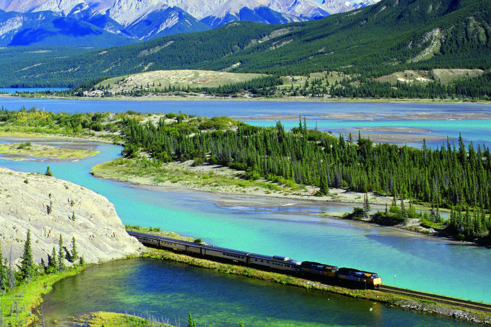 Train traversant la vallée de l’Athabasca entre rivière, forêt et montagnes