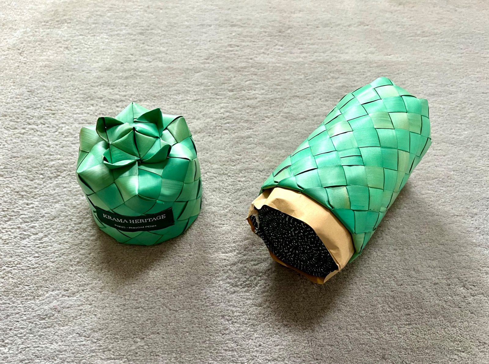 Deux écrins tressés en feuille de palmier vert, l'un fermé en forme de fleur, l'autre ouvert sur un krama roulé.