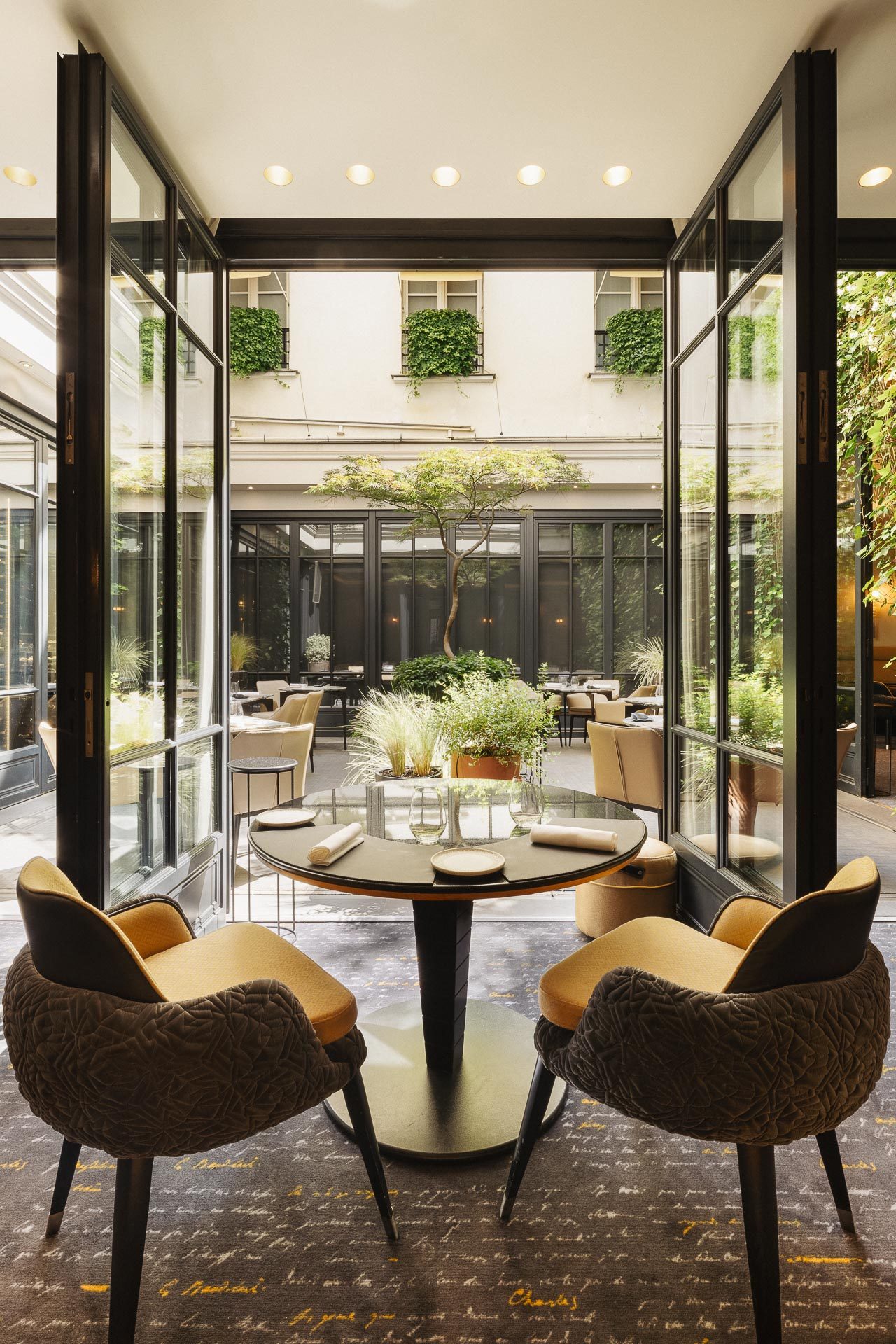 Salle du restaurant Le Baudelaire ouverte sur le patio arboré