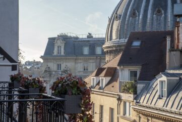 Balcon fleuri du Burgundy Paris face aux toits et au dôme de Notre-Dame-de-l'Assomption