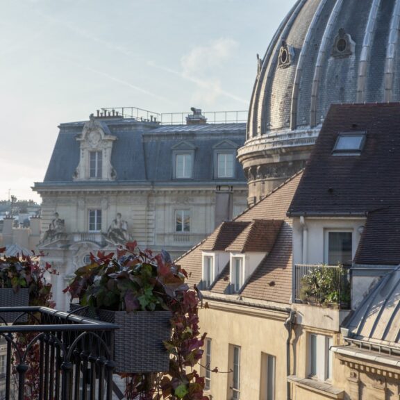 Balcon fleuri du Burgundy Paris face aux toits et au dôme de Notre-Dame-de-l'Assomption