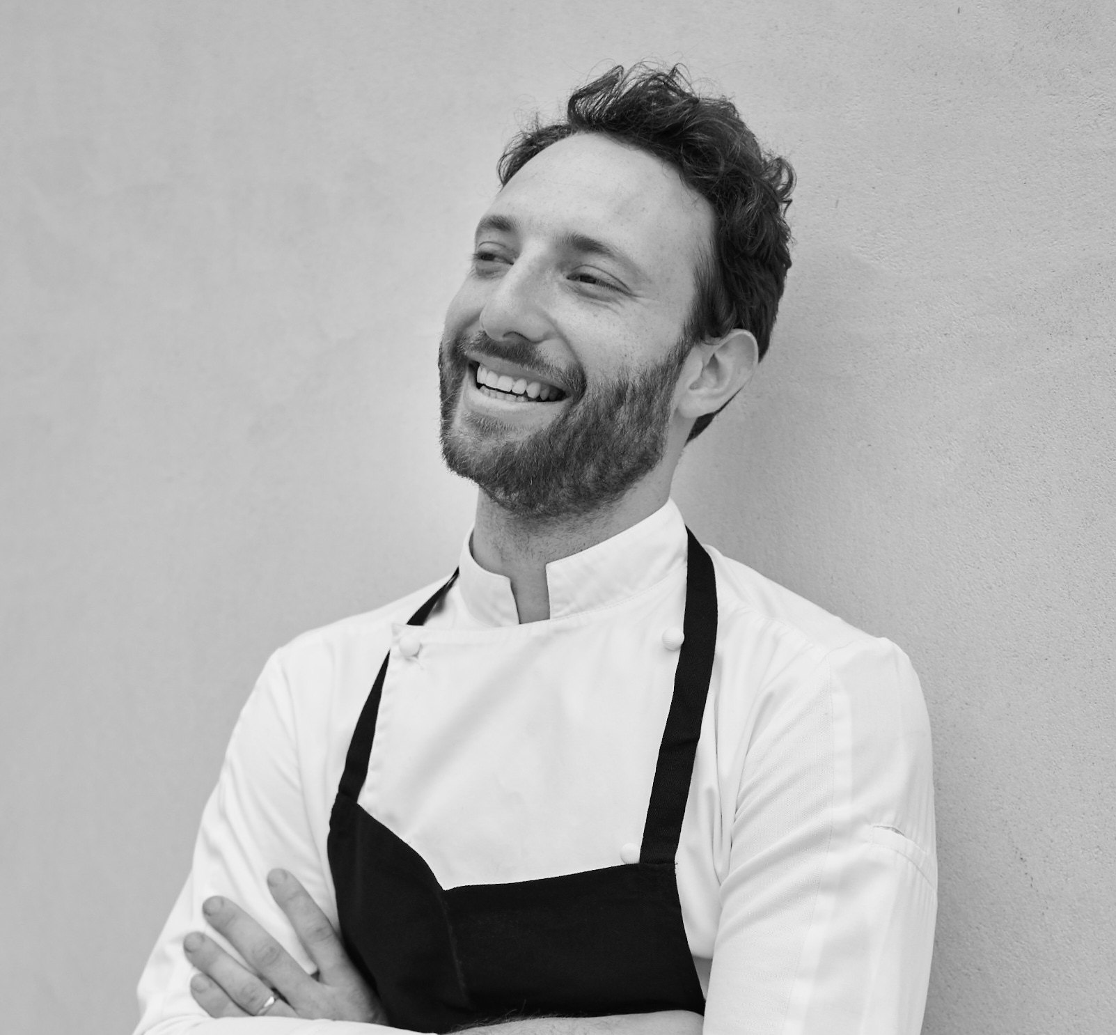 Portrait en noir et blanc du chef Mylo Levin, bras croisés, en veste de cuisine