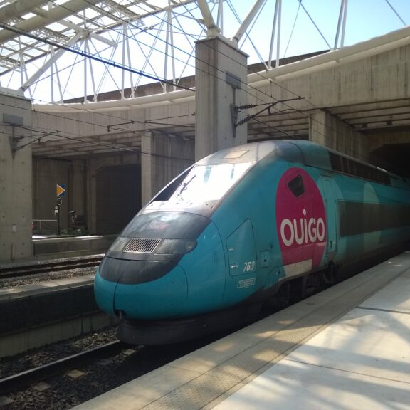 Rame OUIGO bleu turquoise à quai dans la gare Aéroport Charles-de-Gaulle 2 TGV, sous la verrière