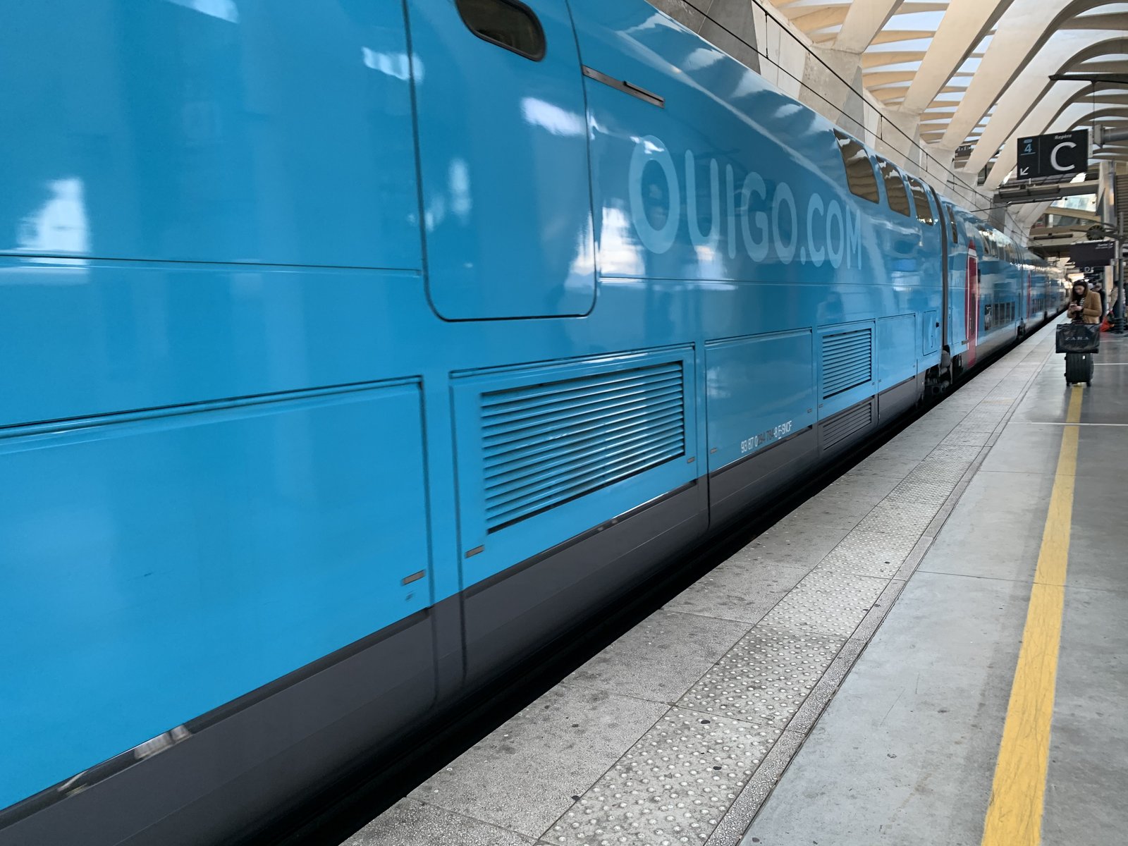 Voiture à étage d'un OUIGO à quai en gare de Lyon-Saint-Exupéry, voyageuse avec valise au fond