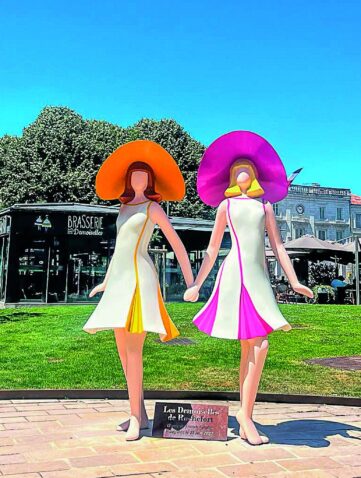 Sculpture des Demoiselles de Rochefort aux chapeaux orange et rose, sur la place Colbert