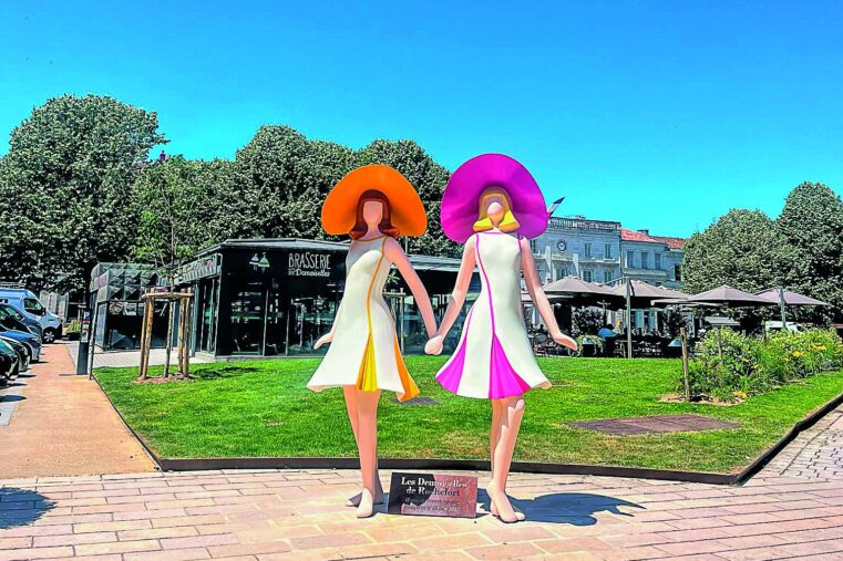 Sculpture des Demoiselles de Rochefort aux chapeaux orange et rose, sur la place Colbert