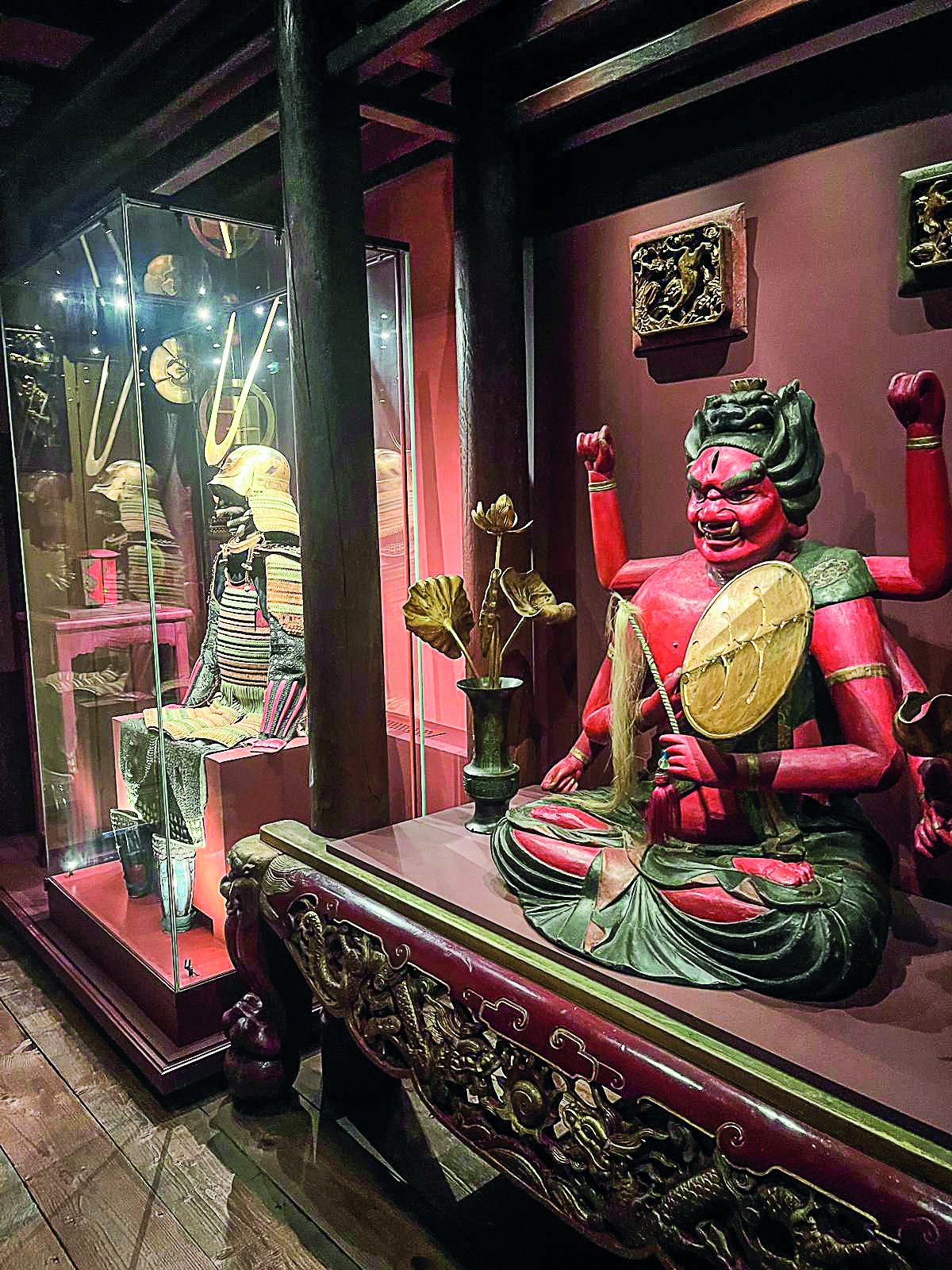 Statue japonaise rouge et vitrine abritant une armure de samouraï dans la maison de Pierre Loti