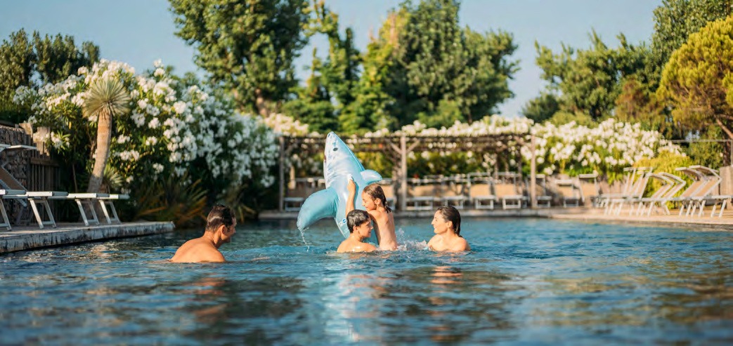 Vacanciers dans la piscine du Sérignan Plage Nature, entourée de lauriers-roses en fleurs